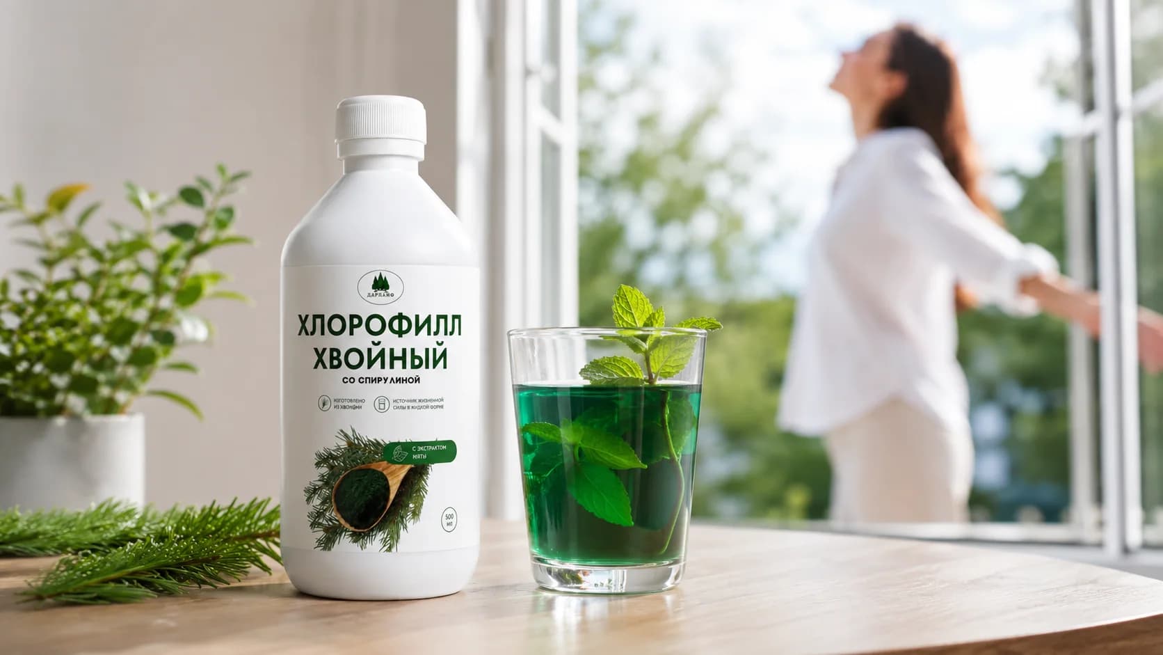 Белая бутылка хвойного хлорофилла и стакан зеленого напитка с мятой на деревянном столе у открытого окна